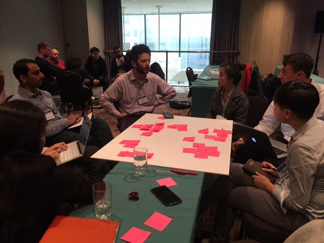 People sitting around a poster board with sticky notes on it