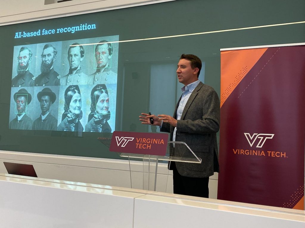 Kurt Luther standing at a podium, speaking, and gesturing in front of a screen with the words "AI-based face recognition" and Civil War-era portraits